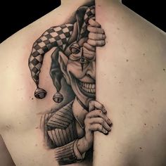 the back of a man's shoulder with a clown tattoo on his left side