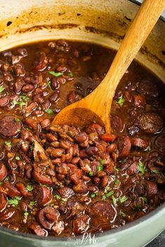 beans and sausage in a pot with a wooden spoon