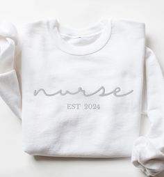 CHRISTMAS DEADLINE: We can no longer guarantee shipment by Christmas. Sorry :(  These unisex cozy sweatshirts (we use Gildan) are embroidered "nurse" in cursive font and your custom year in your choice of thread color 😀 * 50% cotton, 50% polyester * Pre-shrunk * Classic fit * 1x1 athletic rib knit collar with spandex * Air-jet spun yarn with a soft feel and reduced pilling * Double-needle stitched collar, shoulders, armholes, cuffs, and hem SIZING: Please ensure you check measurement chart befo White Letter Embroidery Sweatshirt For Loungewear, White Sweatshirt With Letter Embroidery For Loungewear, White Sweatshirt With Letter Embroidery For Everyday, White Everyday Sweatshirt With Letter Embroidery, White Sweatshirt With Letter Embroidery, Cotton Relaxed Fit Nursing Sweatshirt, Cotton Nursing-friendly Relaxed Fit Sweatshirt, White Relaxed Fit Sweatshirt For Nursing, Cotton Sweatshirt For Nursing In Fall