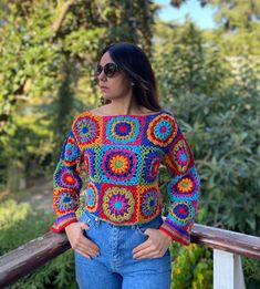 a woman standing next to a wooden rail with her hands on her hips and wearing sunglasses