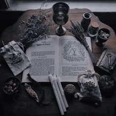 an open book sitting on top of a wooden table next to other items and candles