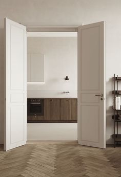 an open door leading to a kitchen with white walls and wood flooring on the other side