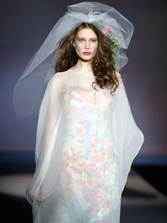 a woman with a veil on her head walking down the runway