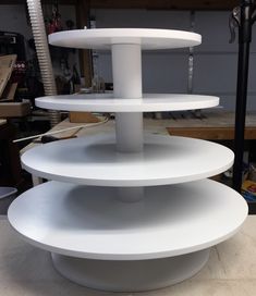 three tiered white cake stand sitting on top of a table