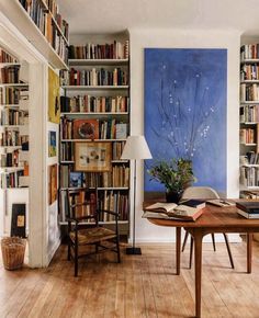 a room filled with lots of books on top of a hard wood floored floor