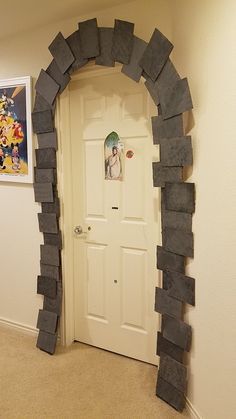 an arch made out of rocks in the corner of a room with a door and pictures on the wall