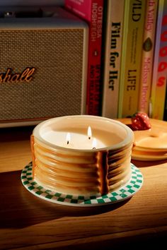 a lit candle sitting on top of a wooden table next to books and an amp