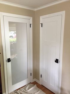 an empty room with two white doors and some sheets on the floor in front of them