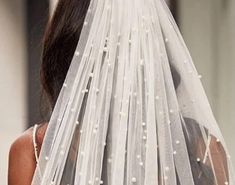 the back of a woman's head wearing a white veil with pearls on it