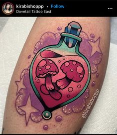 a colorful tattoo design on the leg of a woman's thigh with an image of a heart in a bottle