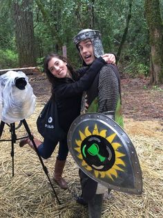 a man and woman posing for a photo in front of a knight's shield