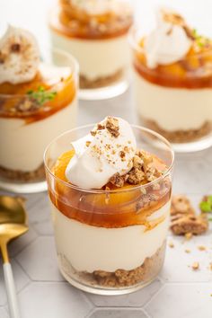 two desserts with fruit and whipped cream in them on a striped table cloth next to a pair of scissors