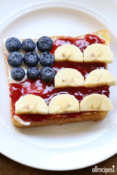 an american flag toast with blueberries and banana slices on it, sitting on a white plate