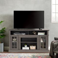 a large flat screen tv sitting on top of a wooden entertainment center next to a chair