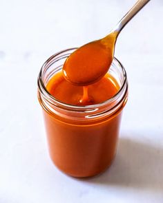 an orange liquid in a glass jar with a spoon