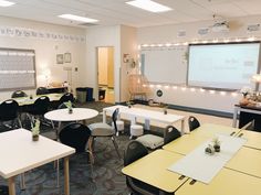 a classroom with tables, chairs and a projector screen