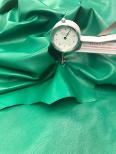 a close up of a green cloth with a small clock on the end of it