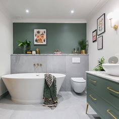 a bathroom with green walls and white fixtures, including a large bathtub in the center