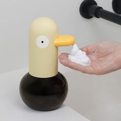 a hand is holding a bottle with cream on it and a duck shaped soap dispenser