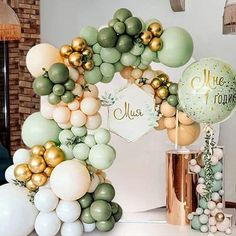 the balloon arch is decorated with gold, white and green balloons