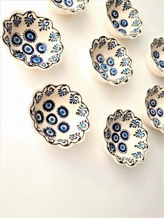 six blue and white dishes with eyeballs on the lids are arranged in a circle