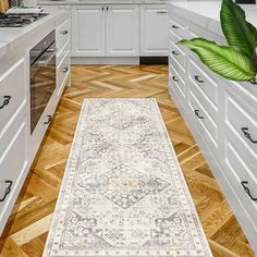 a kitchen with white cabinets and wooden flooring has an area rug on the floor