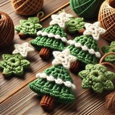 crocheted christmas tree ornaments on a wooden table next to twine balls and yarn