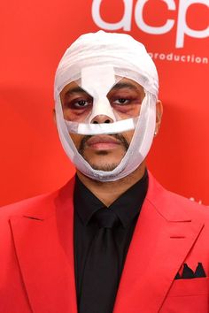 a man in a red suit with a white mask on his face and tape around his nose