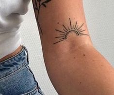 a woman's arm with a sun and flower tattoo on the left side of her arm