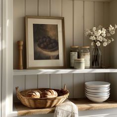 a basket on a shelf next to some plates and other items in front of a painting