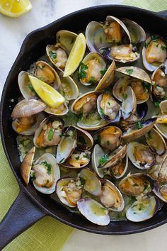 a skillet filled with clams and lemon wedges