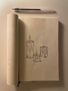 a pencil drawing of two candles on top of a piece of paper next to a pen