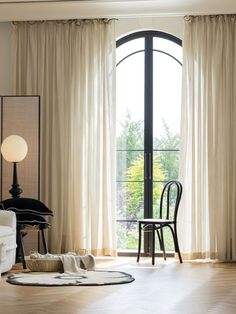 a living room filled with furniture and a large window covered in white drapes