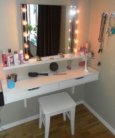 a white dressing table with lights on it