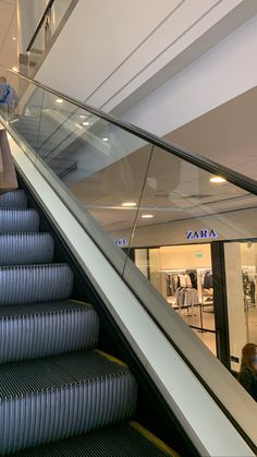 an escalator in a shopping mall with people walking up and down the stairs