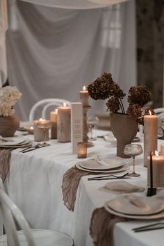 the table is set with white linens and candles