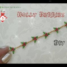 a hand is holding a gold chain with holly berries on it and the words holly berries are