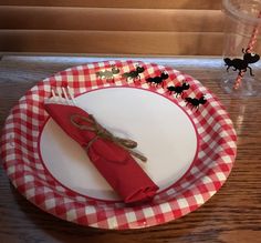 a red and white plate topped with a knife and fork next to a glass cup