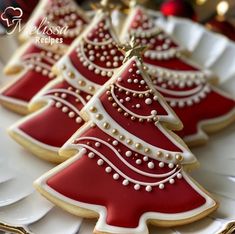 three decorated christmas trees on a white plate with gold trimmings and red icing