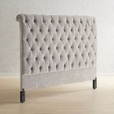 an upholstered headboard with black legs and buttons on the back is shown