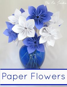 a blue vase filled with paper flowers on top of a table