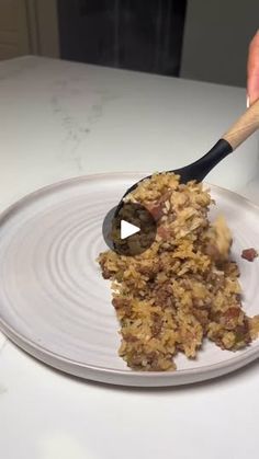 a person scooping food out of a white plate