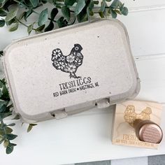 an old tin with a chicken stamp on it next to some leaves and a rubber stamp