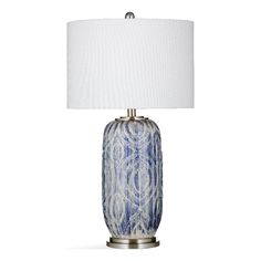 a blue and white table lamp with a white shade on the top, in front of a white background