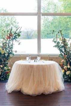 the table is set with two place settings, and there are flowers on either side