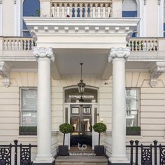 the front entrance to a large white building with columns and pillars on either side of it