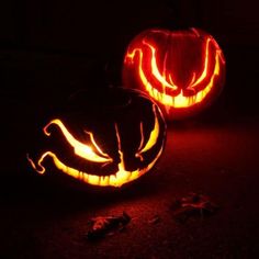 two carved pumpkins sitting on the ground