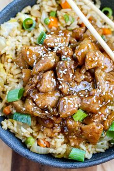 a bowl filled with rice, meat and veggies next to chopsticks