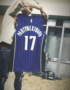 a man holding up a basketball jersey with the number 17 on it