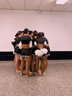 a group of cheerleaders huddle together in a circle